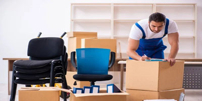 A man fill out a form on boxes with office chairs for a office removals.